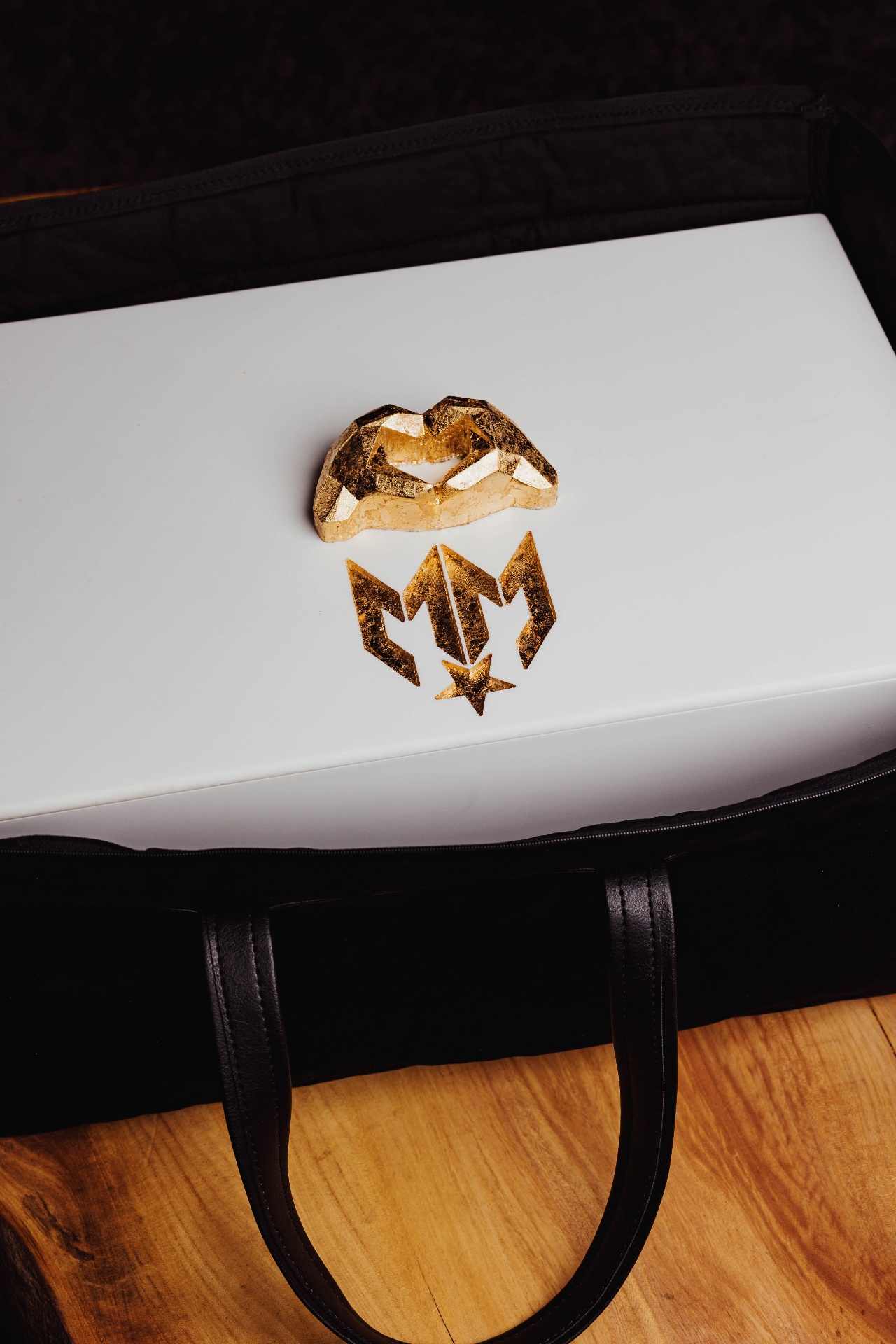 Gold-leaf logo and heart-hands study sat on the box lid