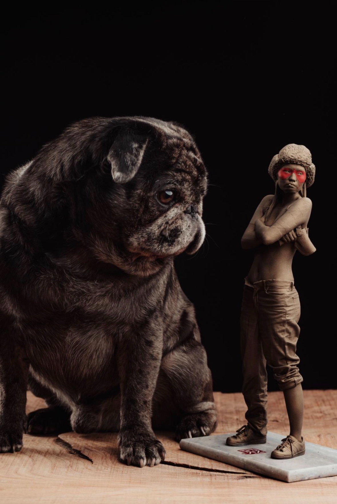 Scale shot — finished bronze edition next to the studio pug for size reference.