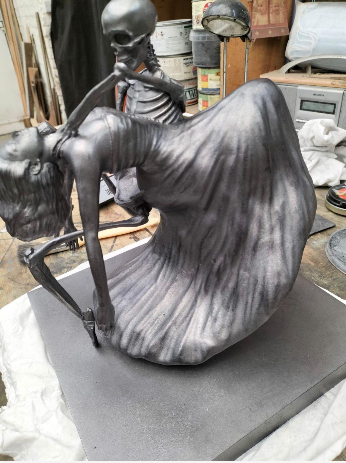 Bronze, side profile — drape and skeleton resolved in metal.