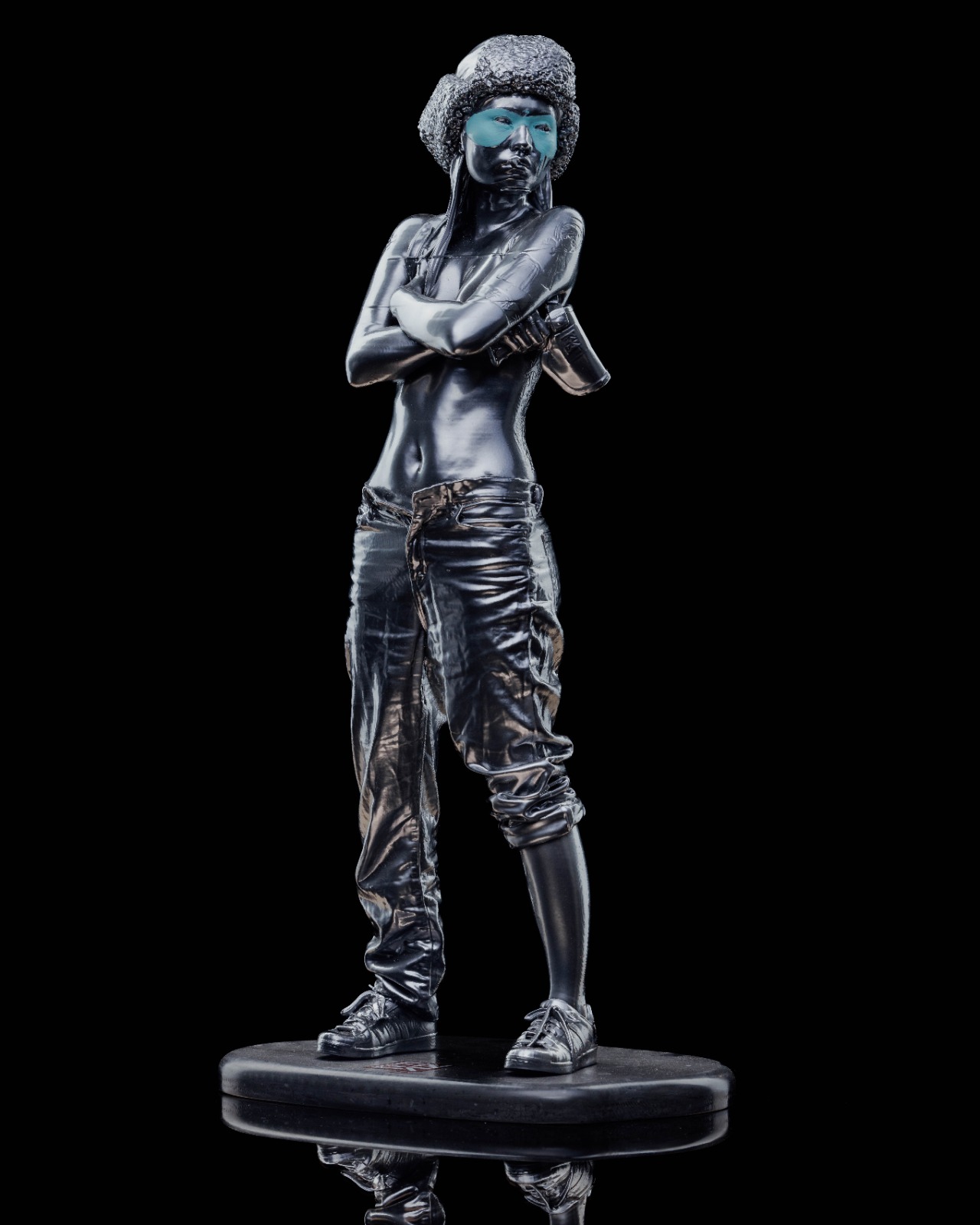 Hero shot — dark chrome figure with hand-painted blue mask, on the round Corian plinth.