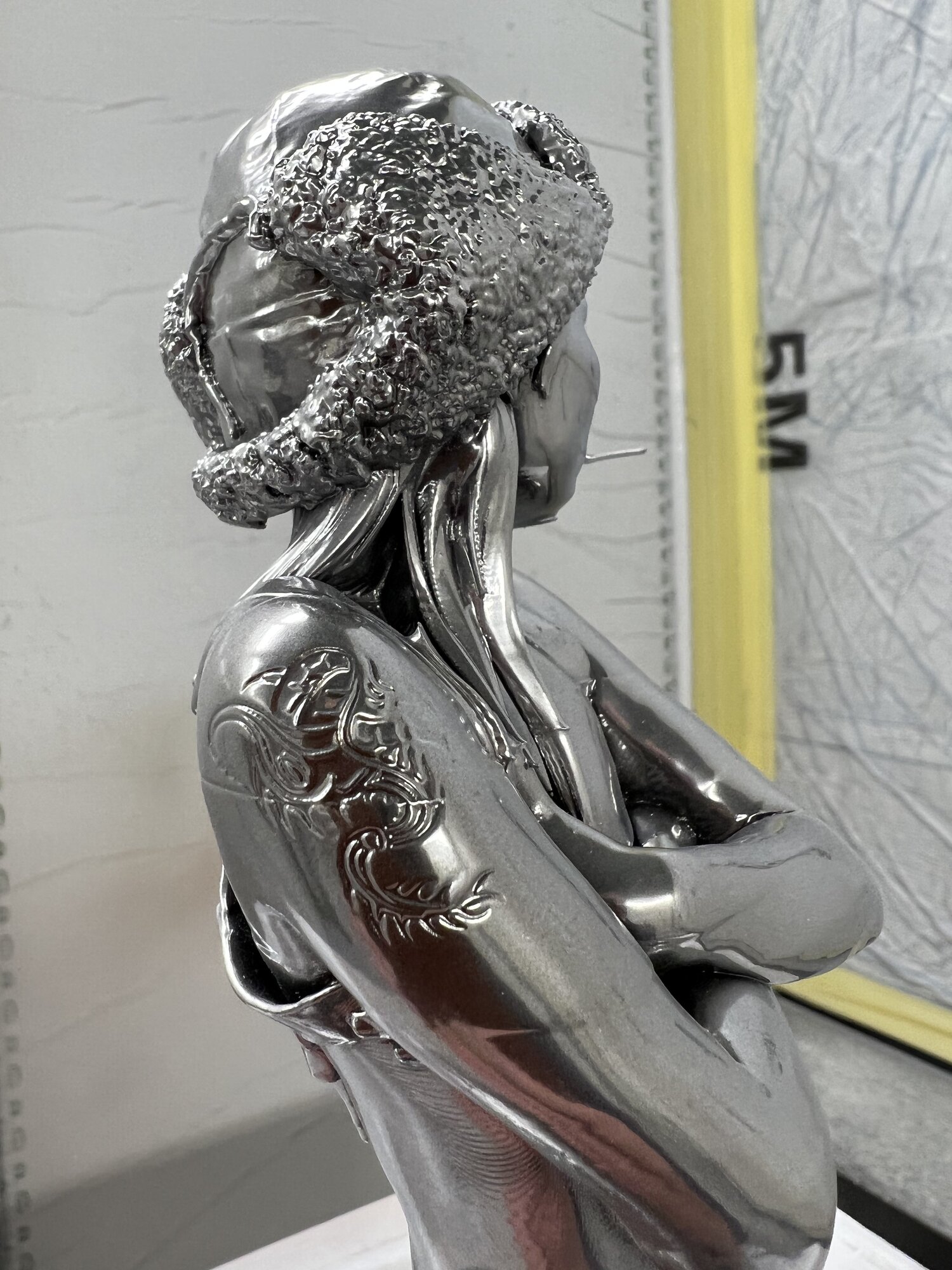 Raw chrome print fresh off the bed — tattoo etching crisp on the shoulder before final finishing.