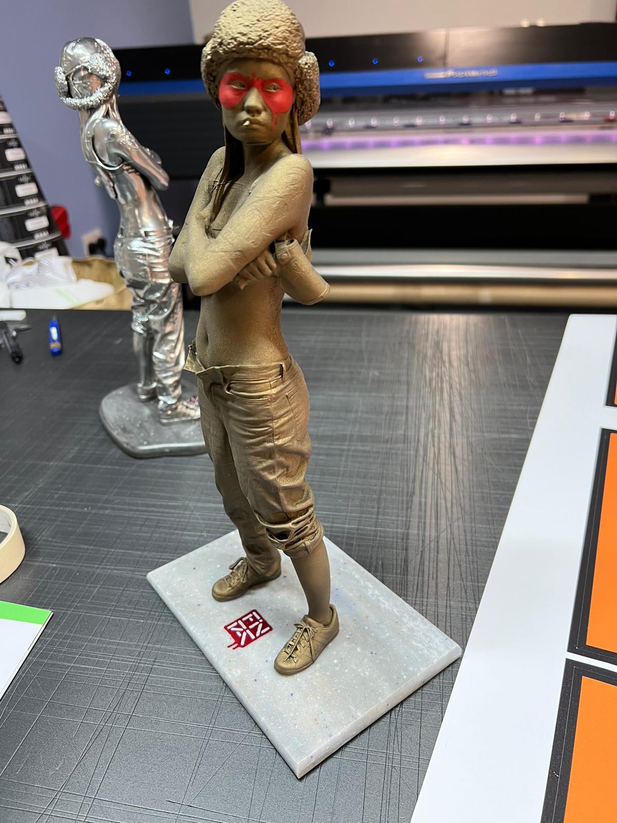 Hand-embellished version on the printer bed — red mask and bleeding tear laid over the bronze finish.