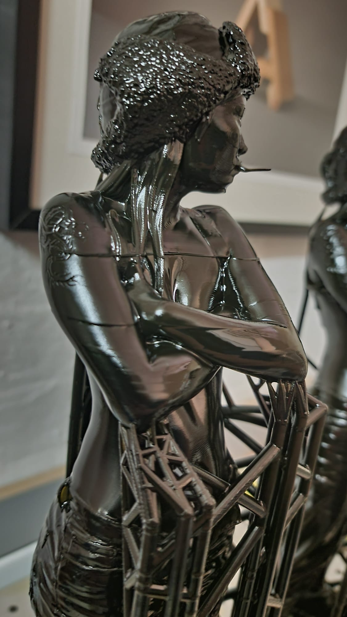 Mid-print on the SLA — body coming up out of the lattice supports, head and shoulders already resolved.